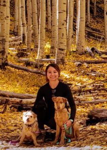 Lauren with her 2 dogs, posing in the forest with white barked aspen trees.
