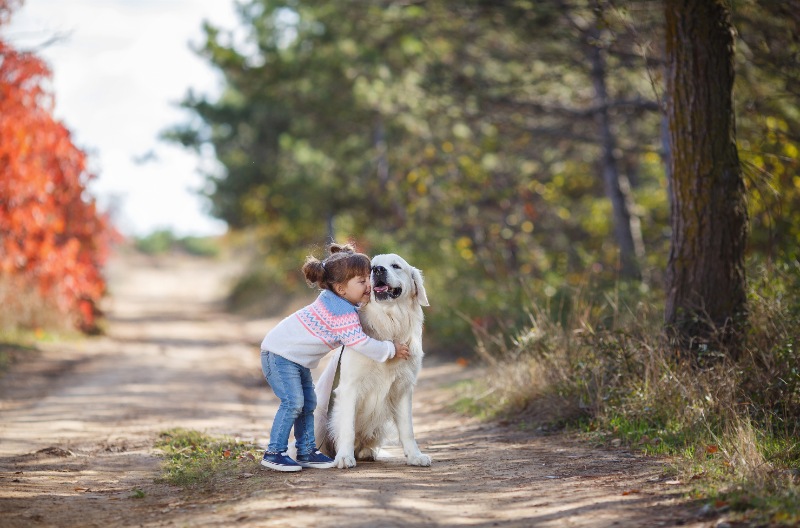 little girl hugging her dog on a trail