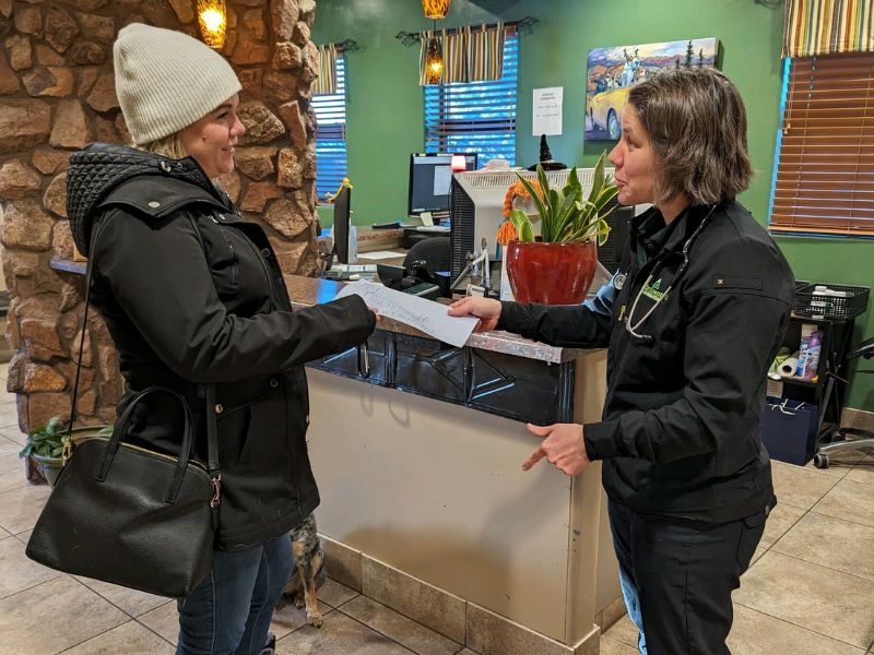 two women in vets office handing document 